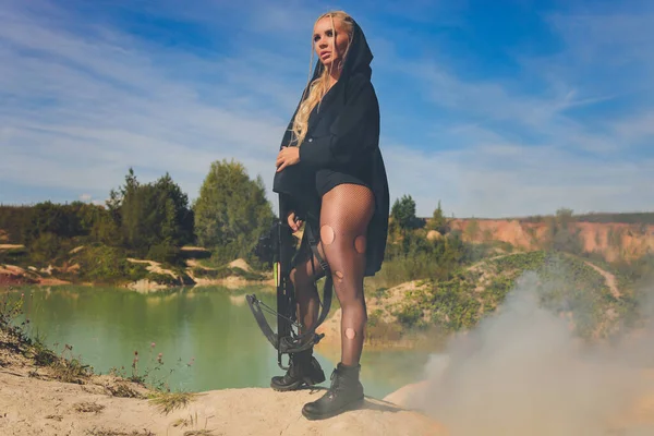 Mulher bonita soldado segurando um rifle de pé sobre uma rocha no céu montanho.blue sol quente. — Fotografia de Stock