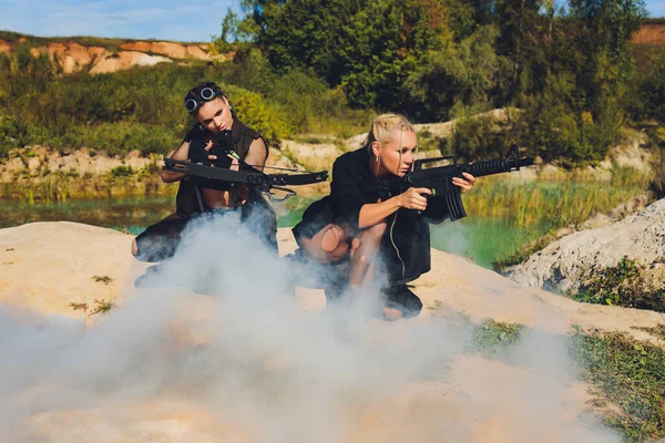 Mulher bonita soldado segurando um rifle de pé sobre uma rocha no céu montanho.blue sol quente. — Fotografia de Stock