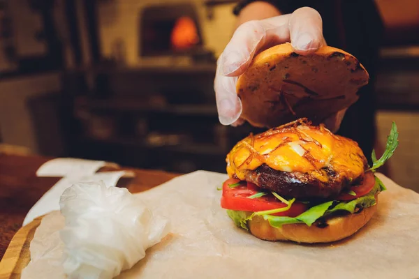 Close-up de delicioso hambúrguer caseiro fresco com alface, queijo, cebola e tomate em uma tábua de madeira rústica em um fundo escuro. Também batatas fritas e Cola com gelo. — Fotografia de Stock