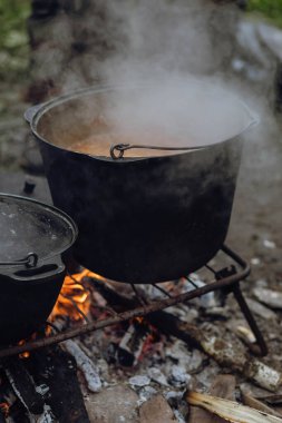 Çaydanlık yürüyüşü, şenlik ateşinde bowling. Kazıkta kazanda balık çorbası kaynıyor. Seyahat, turizm, piknik pişirme, kazanda yemek pişirme, ateş ve duman..
