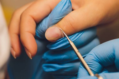 Güzellik salonunda çivi bakımı. Manikürcü kenarları makasla kesiyor. Ellerin muhteşem görünsün..