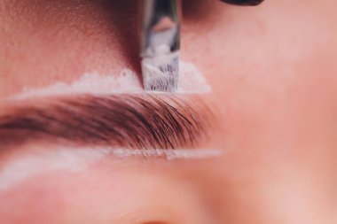 Güzellik salonunda profesyonel kaş düzeltme prosedürü olan genç bir kadın..