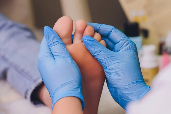 Terapeuta manos en guantes protectores masajeando pies de mujer. — Foto de Stock