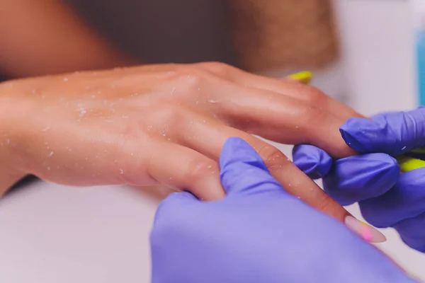 Estetista o manicure in guanti medici speciali provoca la crema sulla mano delle donne. — Foto Stock