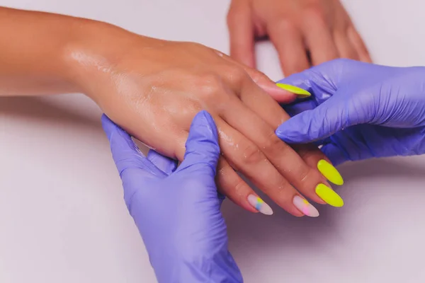 Estetista o manicure in guanti medici speciali provoca la crema sulla mano delle donne. — Foto Stock