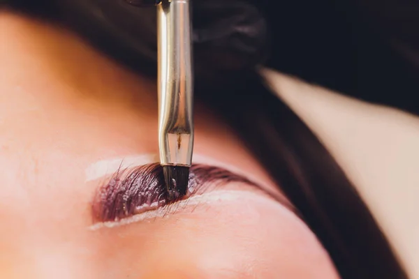 Jonge vrouw met professionele wenkbrauw correctie procedure in schoonheidssalon. — Stockfoto