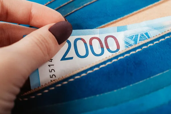 Крупным планом женские руки кладут банкноту в кошелек на тысячи рублей. — стоковое фото