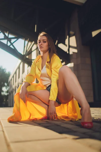 Displaying fashion tendencies. Dark-haired attractive woman posturing in bright yellow fluffy cloak. — Stock Photo, Image