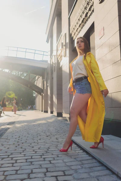 Visualizzazione delle tendenze della moda. Bruna donna attraente postura in giallo brillante soffice mantello. — Foto Stock