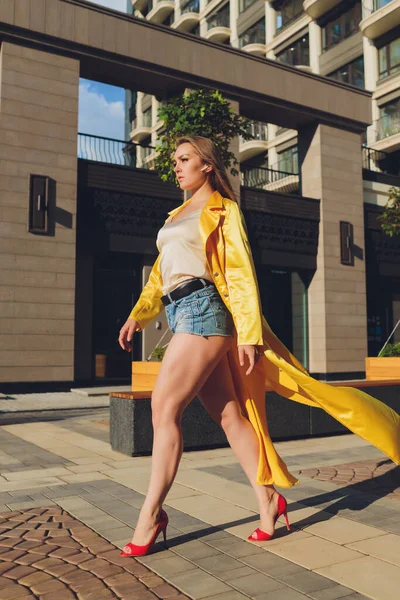 Mostrando tendencias de moda. Mujer atractiva de pelo oscuro posando en una capa mullida de color amarillo brillante. —  Fotos de Stock