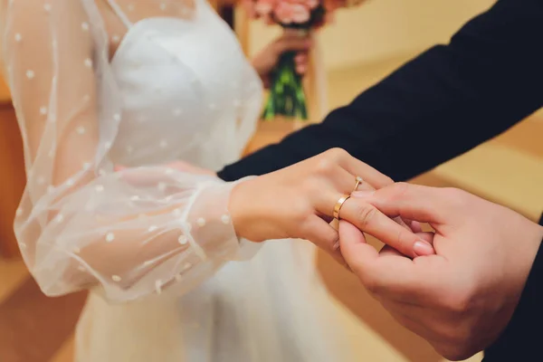 Os recém-casados trocam anéis, o noivo coloca o anel na mão das noivas no cartório do casamento.. — Fotografia de Stock