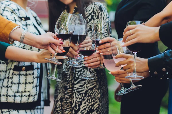 Közelkép emberek csoportjáról, akik poharakat csörömpölnek borral vagy pezsgővel bokeh háttér előtt. idős emberek kezei. — Stock Fotó