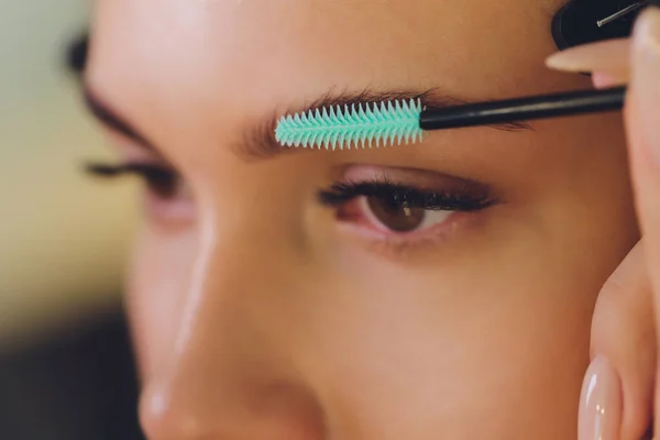 Ung kvinna med professionell ögonbrynskorrigering förfarande i skönhetssalong. — Stockfoto