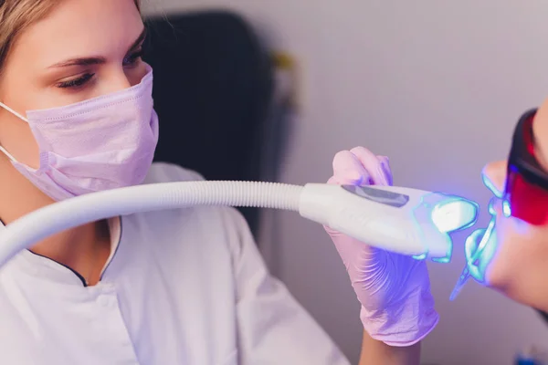 Primo piano ritratto di una paziente in visita dal dentista per lo sbiancamento dei denti in clinica, procedura di sbiancamento dei denti. — Foto Stock