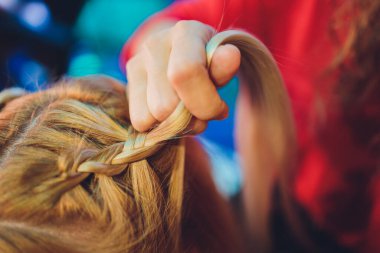 Güzellik salonundaki sarı saçlı küçük kıza örgü ördürme işlemi çok yakın. Profesyonel saç bakımı ve saç modelleri.