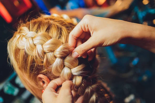 마스터가 땋는 과정은 미용실에 있는 금발의 어린 소녀의 머리에 땋아 줍니다. 전문적 인 모발 관리와 머리 모양을 만드는 일. — 스톡 사진