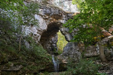 Uçurumdan büyük kaldırım taşları arasında küçük bir dağ nehri şelalesi manzarası.