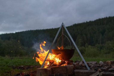 Çaydanlık yürüyüşü, şenlik ateşinde bowling. Kazıkta kazanda balık çorbası kaynıyor. Seyahat, turizm, piknik pişirme, kazanda yemek pişirme, ateş ve duman..