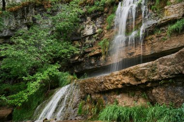 Uçurumdan büyük kaldırım taşları arasında küçük bir dağ nehri şelalesi manzarası.