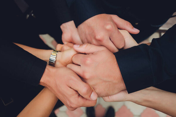 two man and three women holding hands on a table implying a polyamory relationship or love triangle.