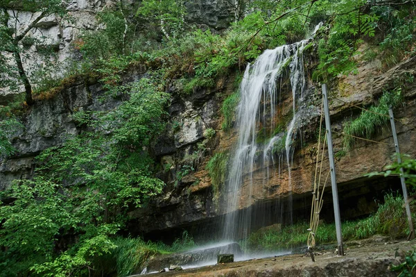 Zicht op een kleine berg rivier waterval tussen grote kasseien van een klif. — Stockfoto