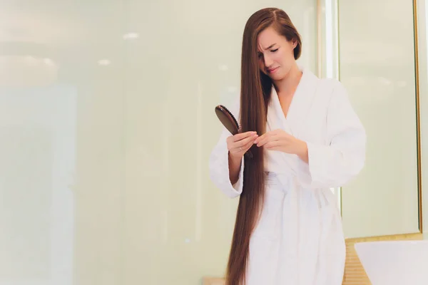 Nahaufnahme einer besorgten jungen Frau, die auf Haarkamm schaut. — Stockfoto