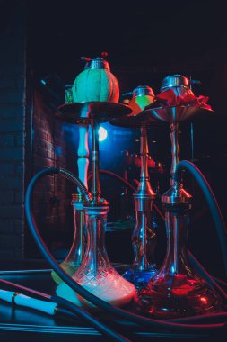Duman ve ahşap masa tuğlasında kırmızı kıvılcımlar olan kırmızı shisha nargilesi, sanat arka planı. Shisha Kavramı.