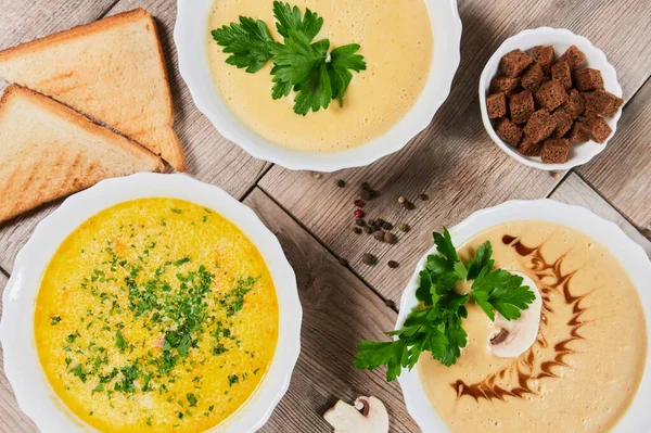 Different kinds of soups - pumpkin soup, cheese cream-soup and mushroom cream-soup on the table. — Stock Image Different kinds of soups - pumpkin soup, cheese cream-soup and mushroom cream-soup on the table. Stock Picture