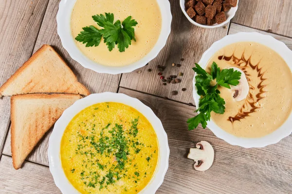 Different kinds of soups - pumpkin soup, cheese cream-soup and mushroom cream-soup on the table. — Stock Image Different kinds of soups - pumpkin soup, cheese cream-soup and mushroom cream-soup on the table. Stock Picture