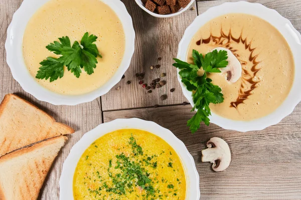 Different kinds of soups - pumpkin soup, cheese cream-soup and mushroom cream-soup on the table. — Stock Image Different kinds of soups - pumpkin soup, cheese cream-soup and mushroom cream-soup on the table. Stock Image