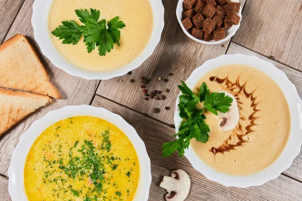 Different kinds of soups - pumpkin soup, cheese cream-soup and mushroom cream-soup on the table. — Stock Image Different kinds of soups - pumpkin soup, cheese cream-soup and mushroom cream-soup on the table. Royalty Free Stock Photos