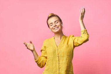 Neşeli dışavurumcu kadın kulaklıkla müzik dinliyor, hoş melodilerden hoşlanıyor, neşeli ruh hali var, tasasız dans ediyor, geniş bir şekilde gülümsüyor..