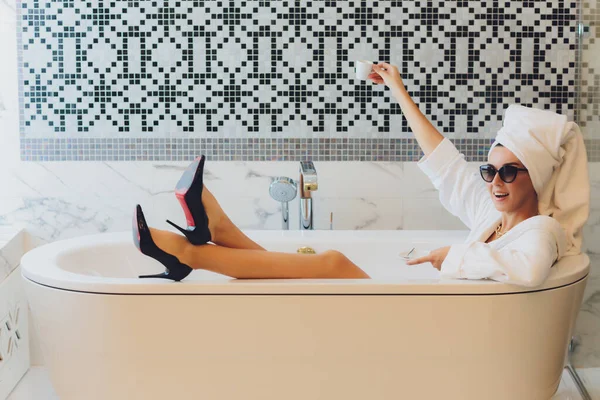 Heerlijk vrouwtje houdt een kopje curatieve drank uitnodigende spa met bad. Rust uit.. — Stockfoto