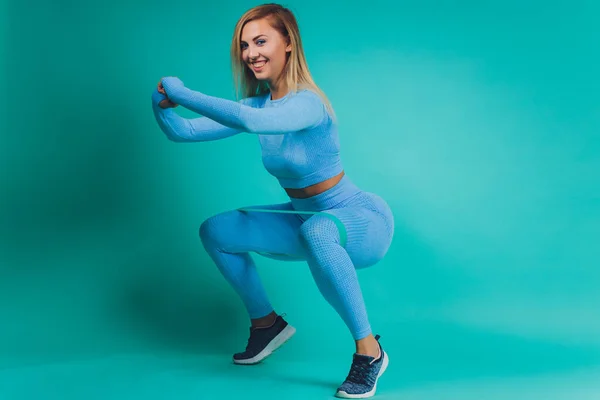 Közelkép sportos fiatal nő izmos test türkiz háttér fénymásolás. Sport és egészséges életmód. — Stock Fotó