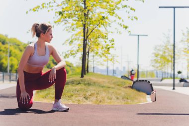 Genç sporcu kadın, esneme hareketleri yapıyor..