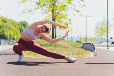 Genç sporcu kadın, esneme hareketleri yapıyor..