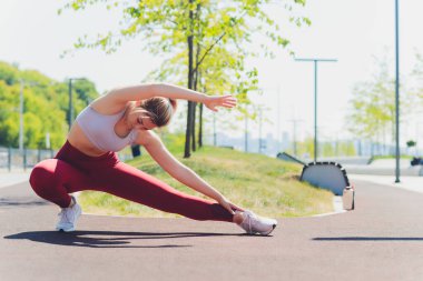 Genç sporcu kadın, esneme hareketleri yapıyor..