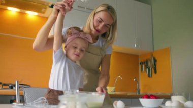 Sevimli bir anne ve kızın portresi mutfakta birlikte bir kız hazırlıyor..