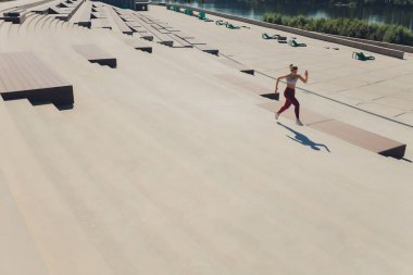 Koşan kadın. Koşucu gün doğumunda koşuyor. Şehrin dışında bir rıhtımda kadın fitness modeli eğitimi. Spor yaşam tarzı.