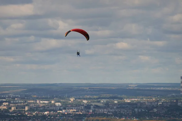 Bir paraglider bulutların arka planında mavi gökyüzünde uçuyor. Güneşli bir günde gökyüzünde paraşütle atlamak. — Stok fotoğraf
