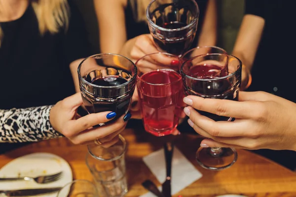 Close-up shot van groep mensen klinkende glazen met wijn of champagne in de voorkant van bokeh achtergrond. handen van ouderen. — Stockfoto