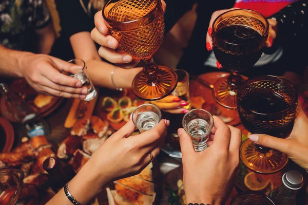 Close up shot of group of people clinking glasses with wine or champagne in front of bokeh background. older people hands.