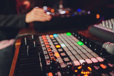 DJ 'lerin eli mikserin üzerinde. DJ 'ler pikaplarda. Bir miksere yakın çekim yap. Karıştırıcı kumandasında Kız Dj.