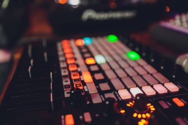 DJ 'lerin eli mikserin üzerinde. DJ 'ler pikaplarda. Bir miksere yakın çekim yap. Karıştırıcı kumandasında Kız Dj.