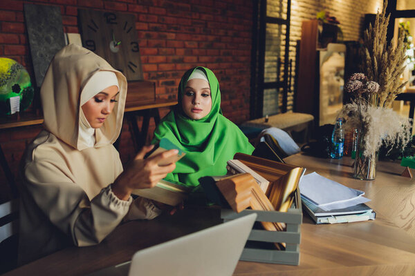 Young muslim asian female designer using graphics tablet while working with computer at studio or office.