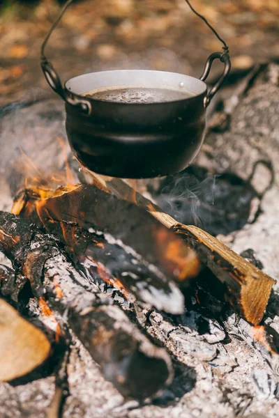 Wandelpot, Bowler in het kampvuur. soep kookt in ketel op de brandstapel. Reizen, toerisme, picknickkoken, koken op de brandstapel in een ketel, vuur en rook. — Stockfoto