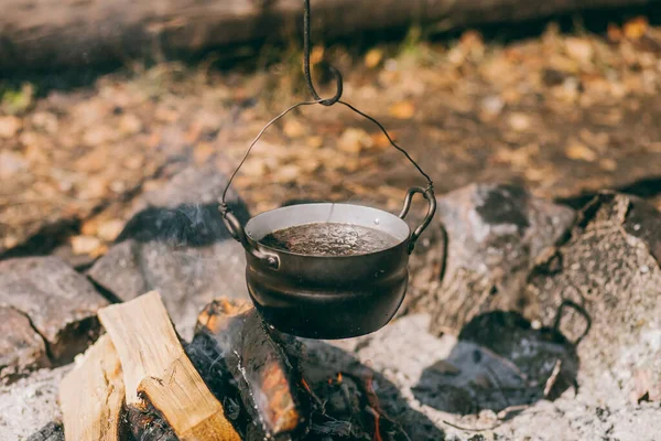 Hiking pot, Bowler in the bonfire. soup boils in cauldron at the stake. Traveling, tourism, picnic cooking, cooking at the stake in a cauldron, fire and smoke.