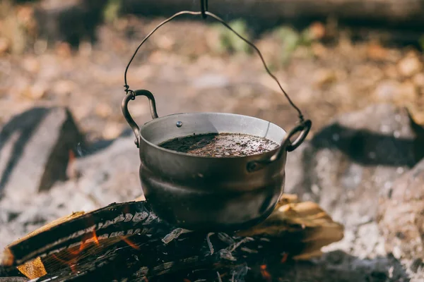 Panela de caminhada, Bowler na fogueira. A sopa ferve em caldeirão na fogueira. Viajar, turismo, piquenique, cozinhar na fogueira em um caldeirão, fogo e fumo. — Fotografia de Stock