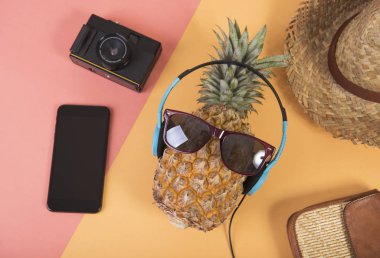 Ananas güneş gözlüğü ve kulaklık üzerinde turuncu arka plan ile. meyve yaz konsepti.