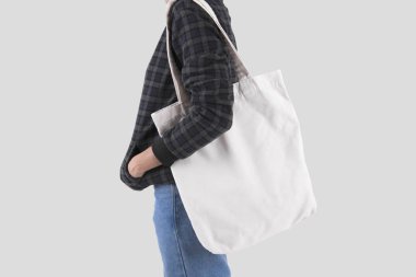 Kız çantası kanvas kumaş mockup boş şablon gri arka plan üzerinde izole için tutuyor. 